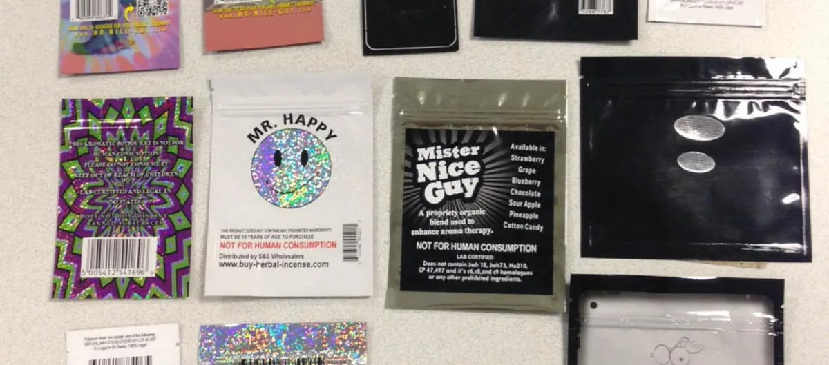 The backs of seized packets. A Mr. Happy packet reads Not for human consumption, distributed by S and S Wholesalers. A Mister Nice Guy packet lists flavours including strawberry, grape, blueberry, chocolate, sour apple, pineapple and cotton candy above the words Not for human consumption, Lab certified.