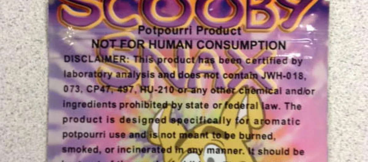 Close-up of a Scooby Snax packet reading Potpourri Product, Not for human consumption, and a disclaimer that it has been certified by laboratory analysis not to contain JWH-018, 073, CP47,497, HU-210 or any chemical prohibited by state or federal law, and is not meant to be burned or smoked.