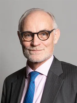Official parliamentary portrait of Crispin Blunt, a grey-haired man with a beard and dark-rimmed glasses, in a dark suit, pink shirt and blue tie.