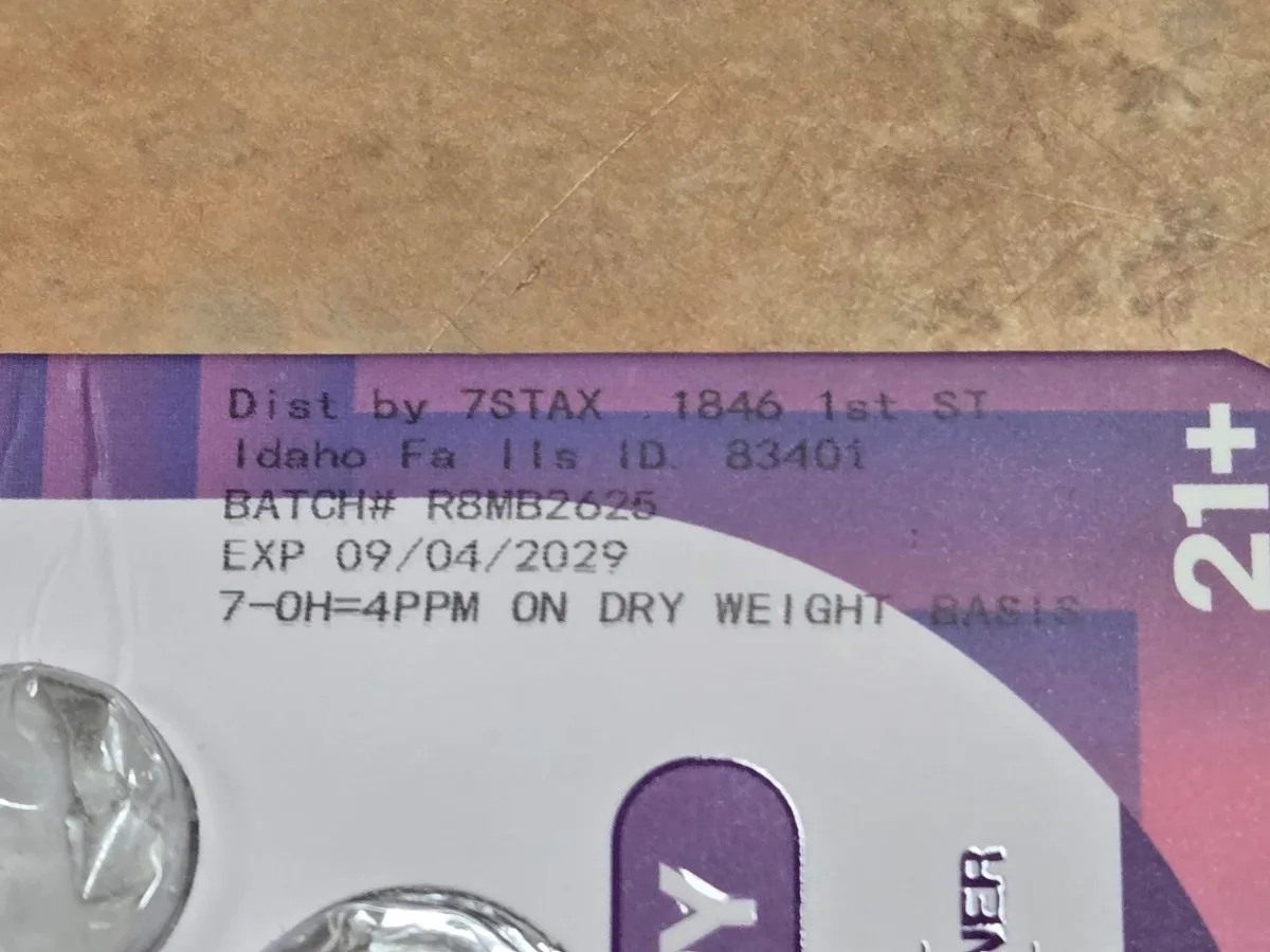 A close-up of the ink-jet print on the back of a purple blister card: Dist by 7STAX 1846 1st ST Idaho Falls ID 83401, BATCH# R8MB2625, EXP 09/04/2029, 7-OH=4PPM ON DRY WEIGHT BASIS.