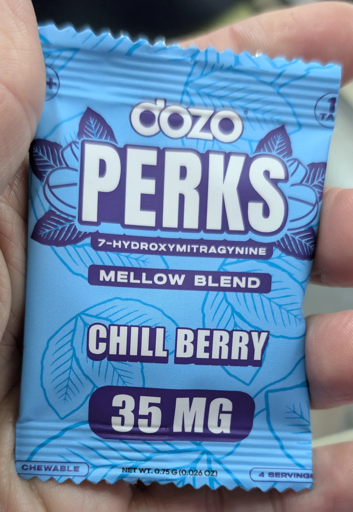 A blue foil single pack held in a hand: dozo PERKS, 7-Hydroxymitragynine, Mellow Blend, Chill Berry, 35 MG, chewable, net weight 0.75 g, 4 servings.