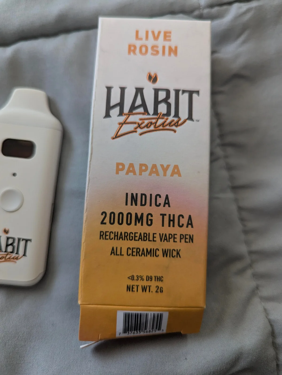 A Habit Exotics Live Rosin Papaya box, Indica, 2000MG THCA, rechargeable vape pen, all ceramic wick, under 0.3% D9 THC, net weight 2 grams, beside the white device.
