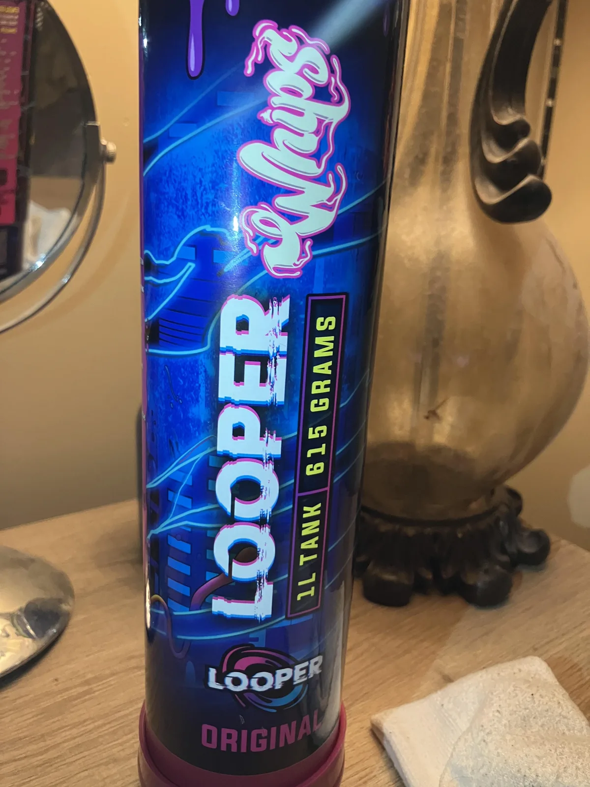 Close view of a blue Looper Whips tank, 1L tank 615 grams, Original, with a neon cityscape design and, at the foot, a round swirl logo reading LOOPER.