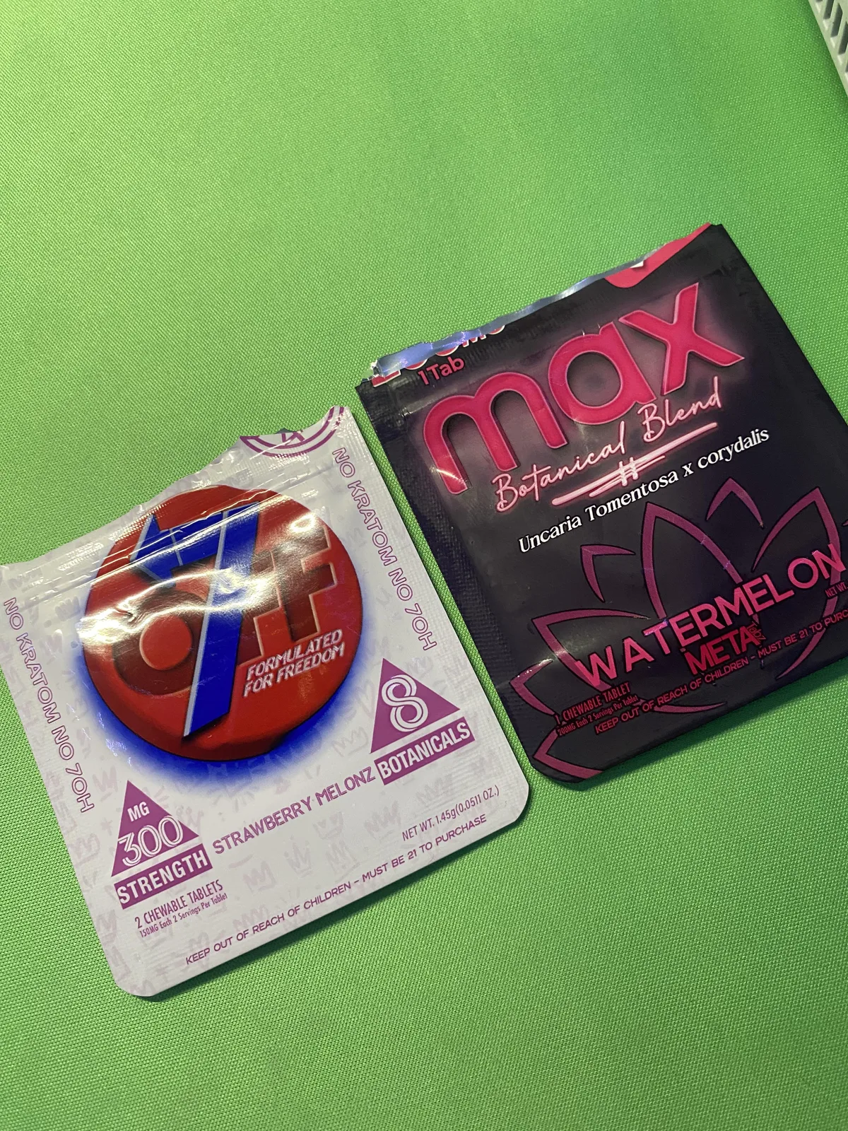 Two pouches on a green surface: a Max Botanical Blend pouch, Watermelon, Uncaria tomentosa x corydalis, META; and an Off7 Botanicals pouch, 300 mg strength, No kratom No 7OH.