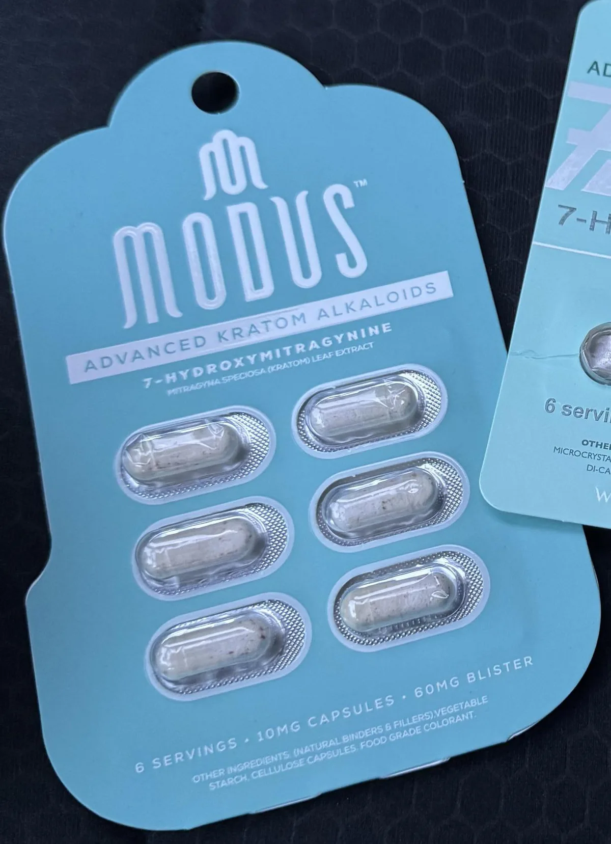 A light blue blister card of six capsules: MODUS, Advanced Kratom Alkaloids, 7-Hydroxymitragynine, Mitragyna speciosa (kratom) leaf extract, 6 servings, 10 mg capsules, 60 mg blister. The capsules hold white powder with brown flecks.