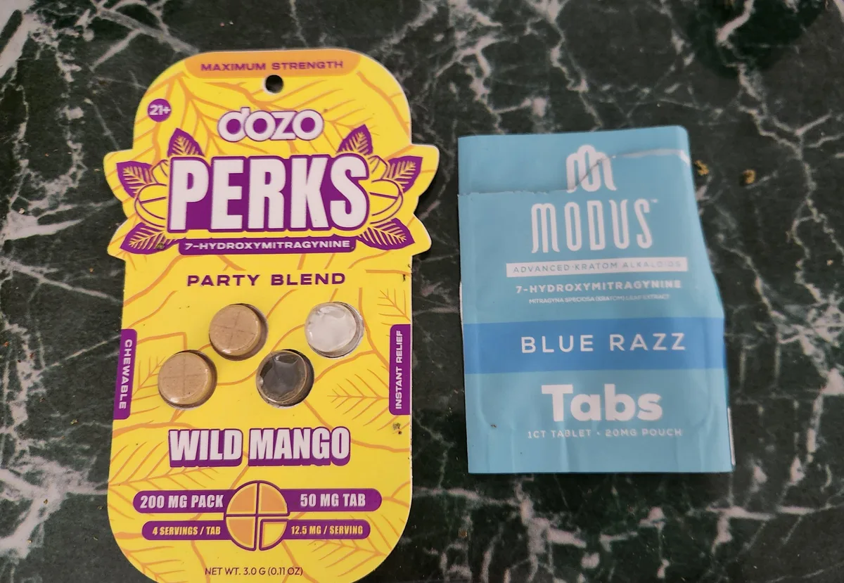 A blue foil pouch, MODUS, Advanced Kratom Alkaloids, 7-Hydroxymitragynine, Blue Razz Tabs, 1 count tablet, 20 mg pouch, beside a yellow Dozo Perks 7-hydroxymitragynine card.