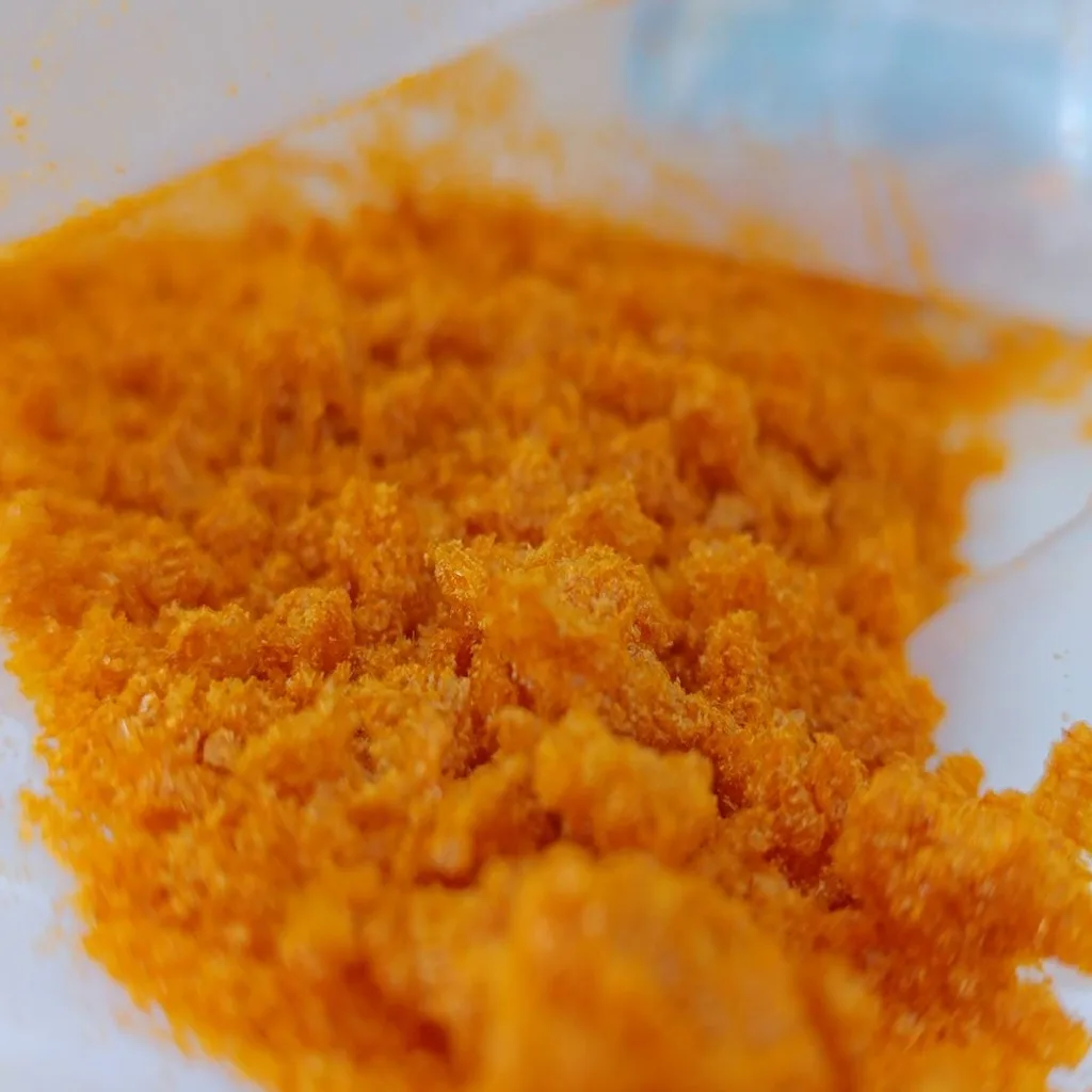 A heap of fluffy orange powder on a white surface.