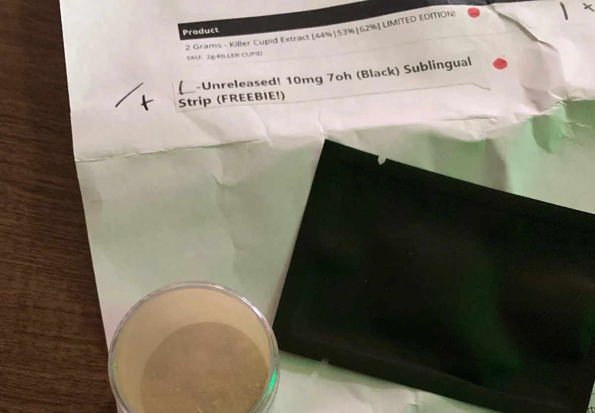 A packing slip reading Unreleased! 10mg 7oh (Black) Sublingual Strip (FREEBIE!) above a plain black sachet and a jar of pale powder.