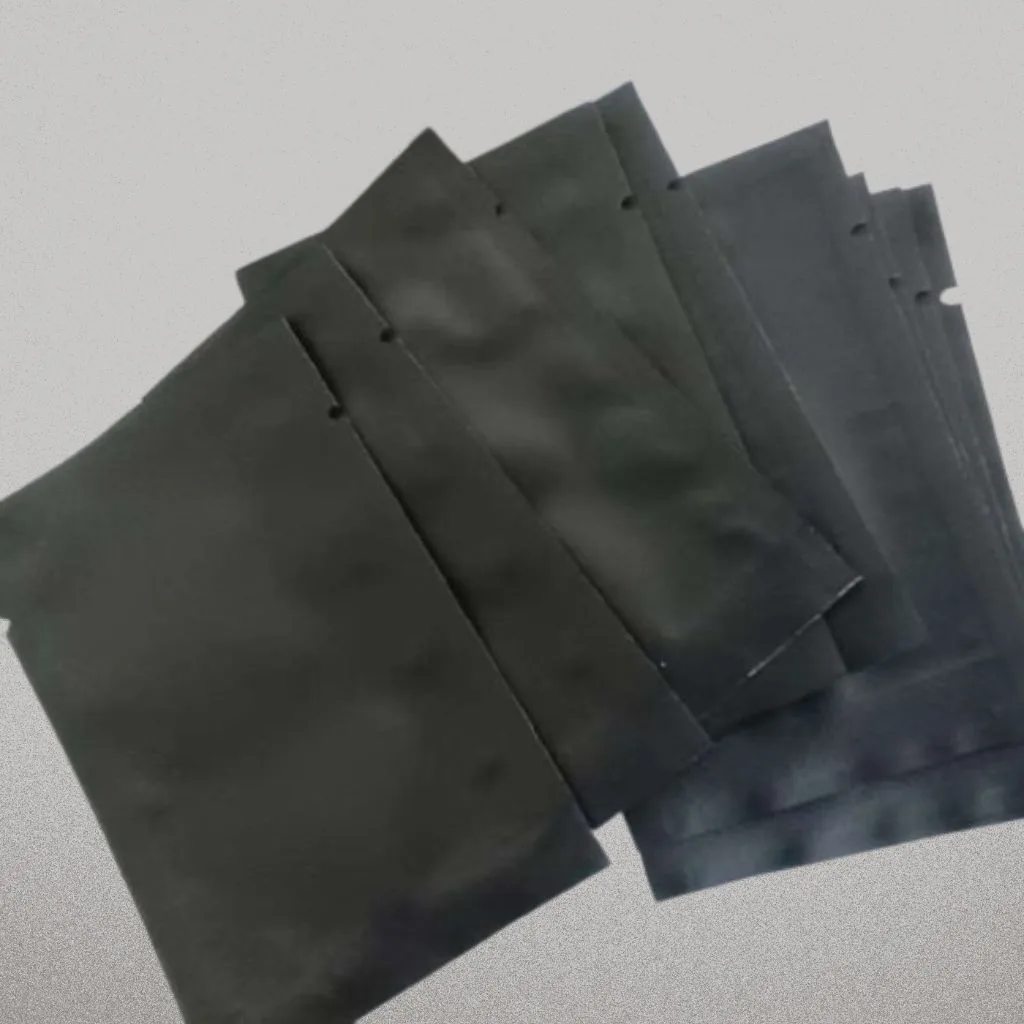 A spread of plain matte black sachets with tear notches and no printing.