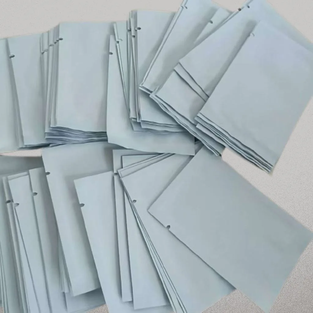 A spread of plain white foil sachets with tear notches and no printing.
