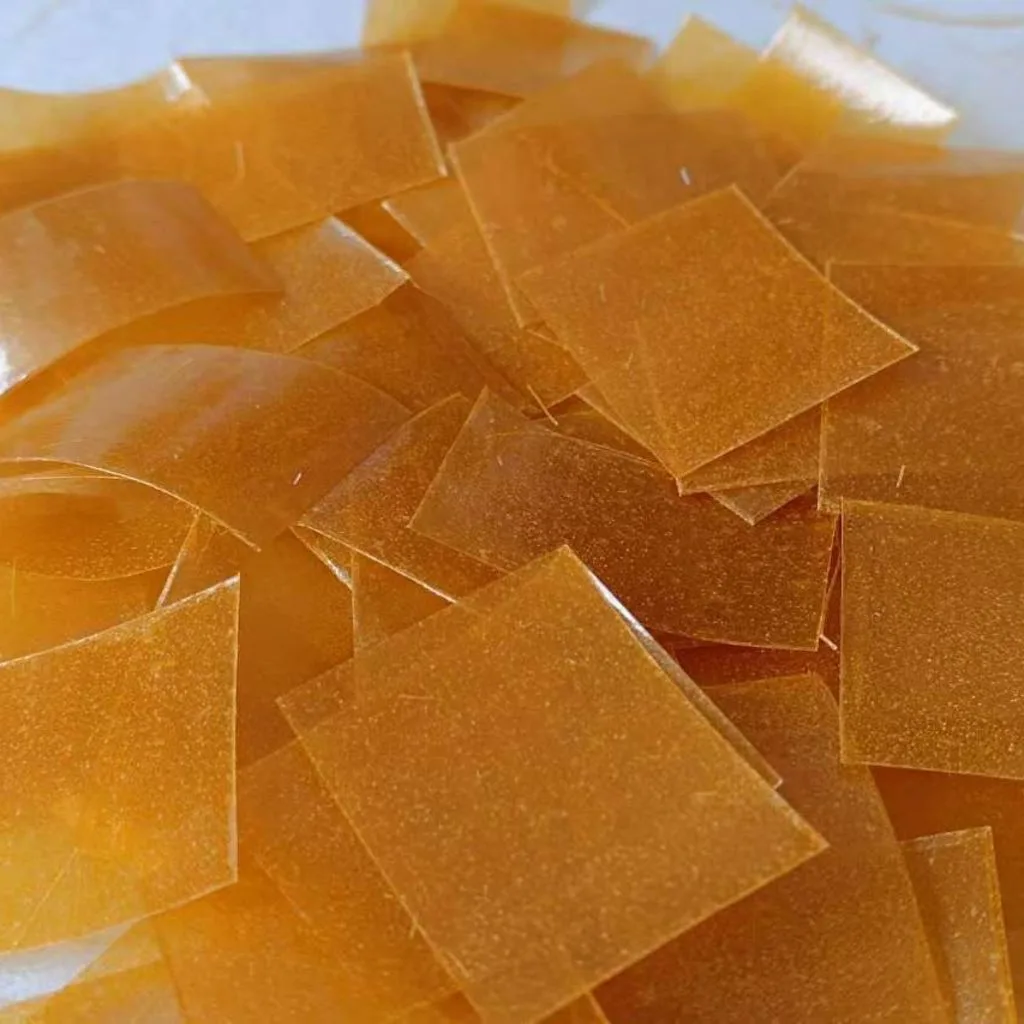 A pile of translucent amber-orange square films on a white background.