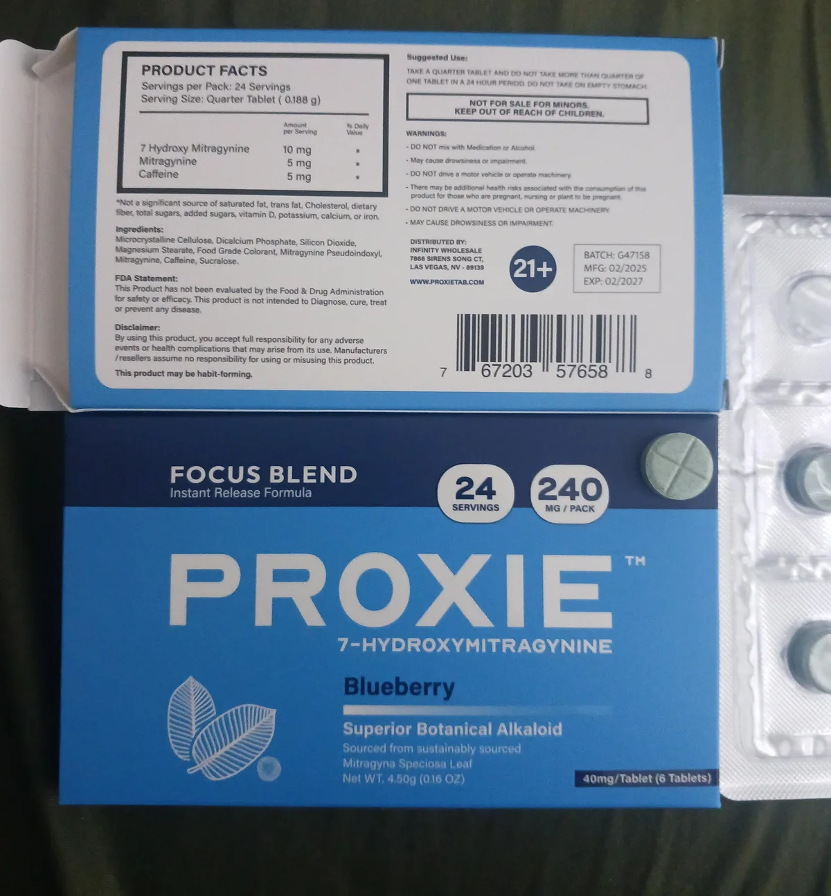 A buyer's photograph of a blue Proxie Focus Blend Blueberry box, 24 servings, 240 mg per pack, 40 mg per tablet, six tablets, with its back panel opened above: Product Facts, a serving of one quarter tablet with 10 mg 7 Hydroxy Mitragynine, 5 mg mitragynine and 5 mg caffeine, an ingredient list, Distributed by Infinity Wholesale of Las Vegas, Nevada, the site address, a 21+ badge, batch G47158 made 02/2025, and a barcode; a blister of green tablets beside it.