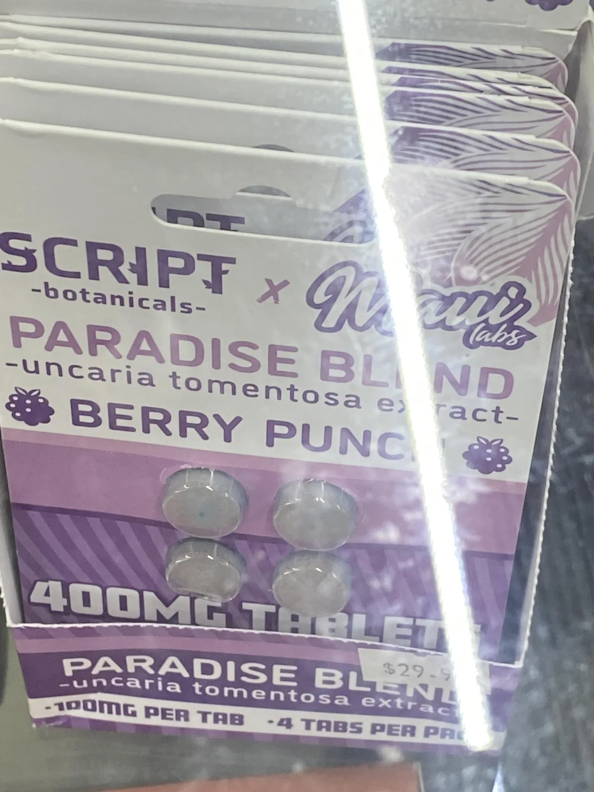 A display of purple blister cards printed SCRIPT -botanicals- x Maui labs, PARADISE BLEND -uncaria tomentosa extract-, BERRY PUNCH, 400MG TABLETS, 100MG PER TAB, 4 TABS PER PACK, with four bluish tablets visible.